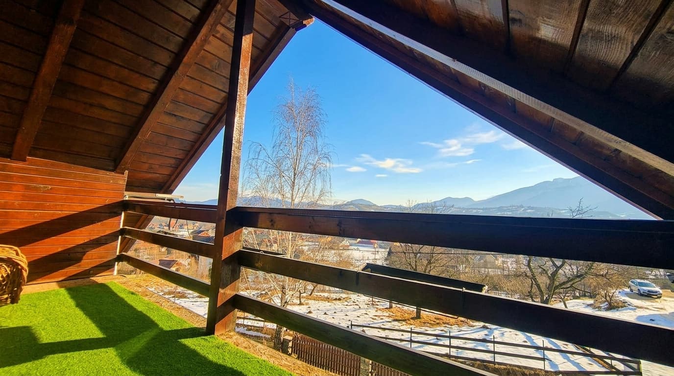 Priveliște spre munți de pe balconul mansardei, sub streașina de lemn